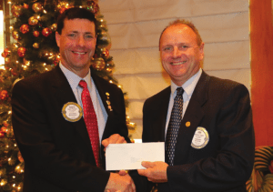 Past President Jim Hunt presents the club with a matching funds check from the Engelstad Foundation for $15,500 to help support our Santa Clothes program.