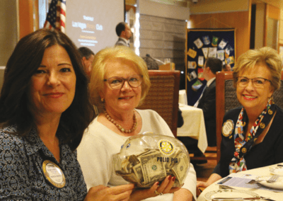 Past Presidents Ginger Anderson and Caty Crockett “Pass-the-Pig” with Carolyn Sparks to help End Polio Now.
